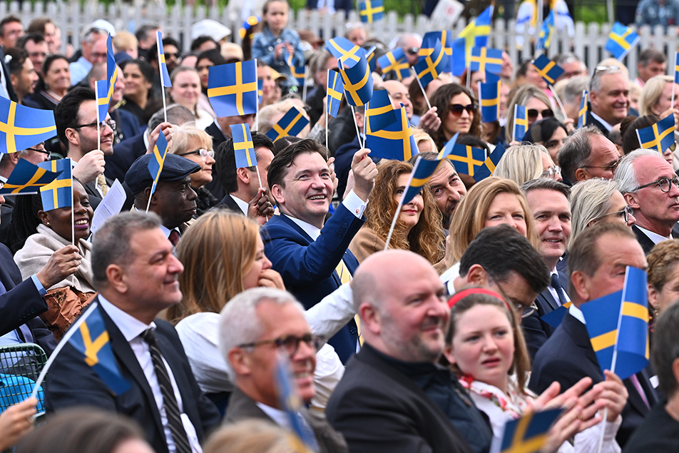 Nationaldagsfirare på Skansne som viftar med svenska flaggor.