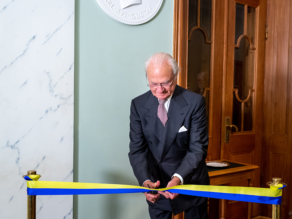 The King cuts the ribbon in front of the new portrait medallion at the Riksdag building.