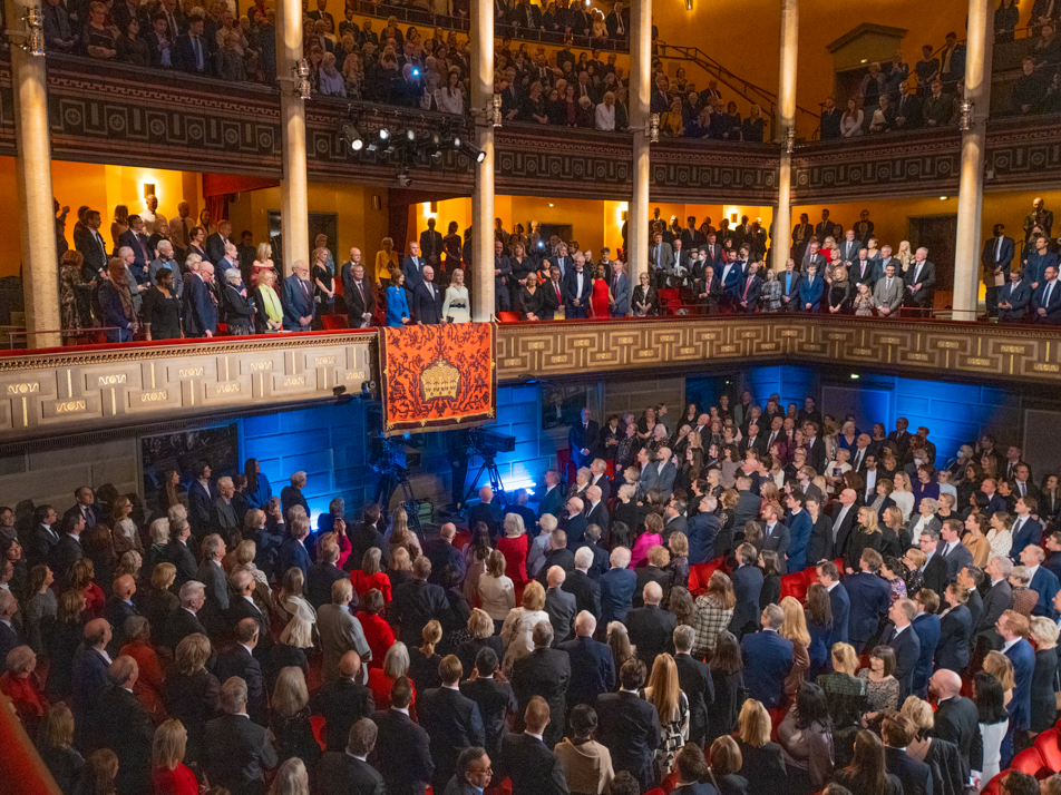 Publiken i Stockholms konserthus hälsar Kungaparet.