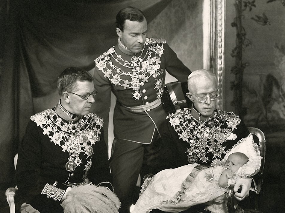 Kungen fotograferad med, från vänster, sin farfar kronprins Gustaf (VI) Adolf, sin far arvprins Gustaf Adolf och sin farfars far, kung Gustaf V i samband med dopet den 7 juni 1946.